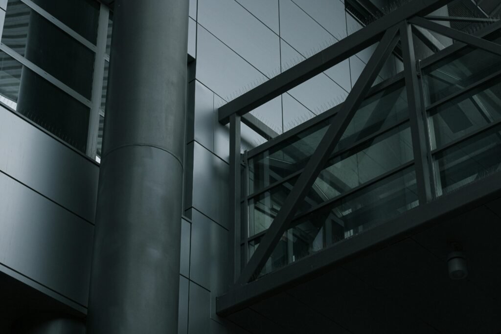 Ein hoher Metallmast steht unmittelbar neben einem mehrstöckigen Gebäude im städtischen Raum.