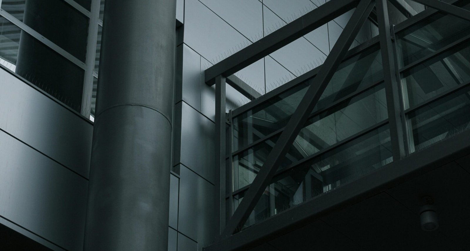 Ein hoher Metallmast steht unmittelbar neben einem mehrstöckigen Gebäude im städtischen Raum.