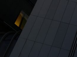 Großes Hochhaus mit integrierter Uhr an der Seite in einer Stadt, fotografiert aus der Froschperspektive