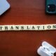 Ein Holzblock mit der Aufschrift Translation liegt auf einem hellen Untergrund und symbolisiert Übersetzung und Sprache.