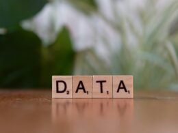 Holzblock mit dem Schriftzug DATA auf einem Tisch, symbolisch für digitale Datennutzung und Technologie