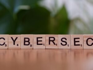 Ein Holzblock mit den Buchstaben 'cybersec' liegt auf einem Tisch und steht symbolisch für Cybersicherheit und IT-Schutz.
