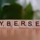 Ein Holzblock mit den Buchstaben 'cybersec' liegt auf einem Tisch und steht symbolisch für Cybersicherheit und IT-Schutz.
