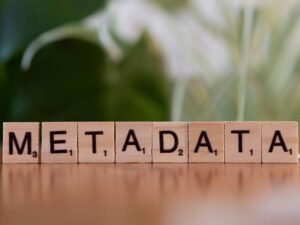 Holzblock mit dem Aufdruck 'metadata' auf einem Tisch als Symbol für Datenorganisation und SEO-Grundlagen.