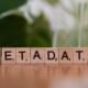 Holzblock mit dem Aufdruck 'metadata' auf einem Tisch als Symbol für Datenorganisation und SEO-Grundlagen.