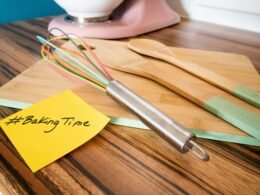 Ein Holzarbeitstisch mit einem Schneebesen und einem gelben Haftnotizzettel als Symbol für Kreativität und Planung