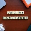 Scrabble-Steine auf einem Holztisch buchstabieren 'Online Languages' und stellen digitale Sprachlernoptionen dar