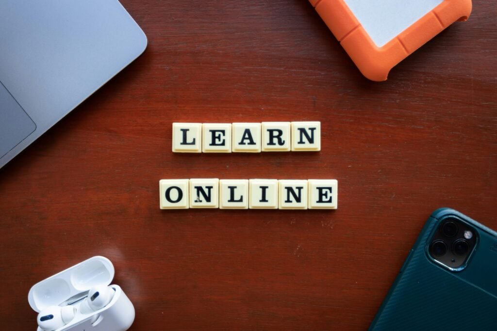 Scrabble-Buchstaben auf einem Holztisch bilden den Schriftzug 'Learn Online' als Sinnbild für digital unterstütztes Lernen.