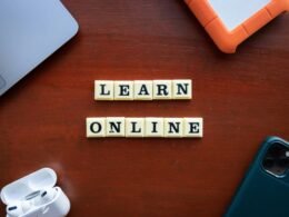 Scrabble-Buchstaben auf einem Holztisch bilden den Schriftzug 'Learn Online' als Sinnbild für digital unterstütztes Lernen.