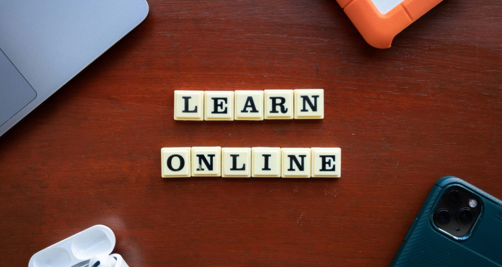 Scrabble-Buchstaben auf einem Holztisch, die 'Learn Online' buchstabieren. Symbol für digitales Lernen und Online-Bildung.