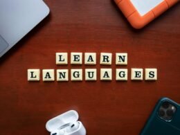 Auf einem Holztisch liegen Scrabble-Steine, die das Wort Learn Languages bilden und Sprachenlernen symbolisieren.