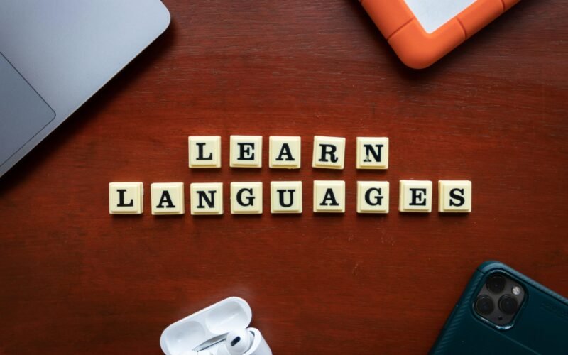 Auf einem Holztisch liegen Scrabble-Steine, die das Wort Learn Languages bilden und Sprachenlernen symbolisieren.