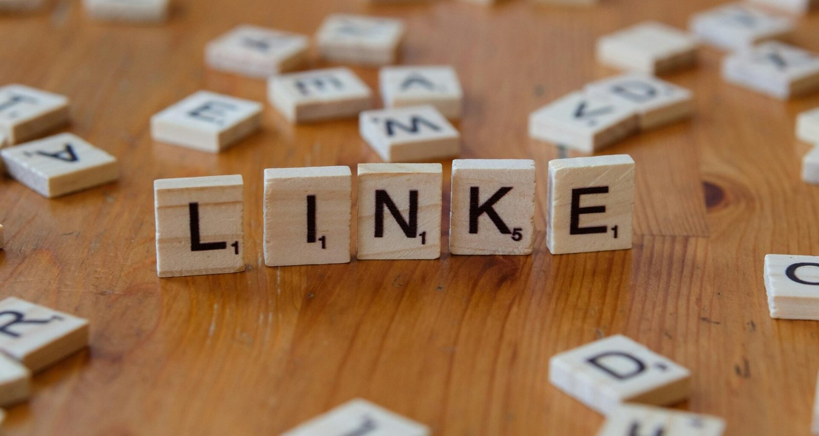 Holztisch mit Scrabble-Steinen, die das Wort Link darstellen, geeignet als Symbolbild für SEO- und Online-Marketing-Inhalte.