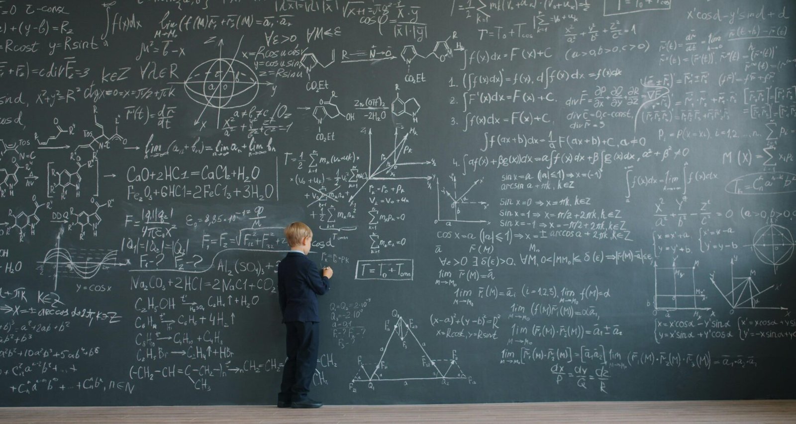 Junge steht vor einer Schultafel, die vollständig mit mathematischen Gleichungen und Formeln bedeckt ist