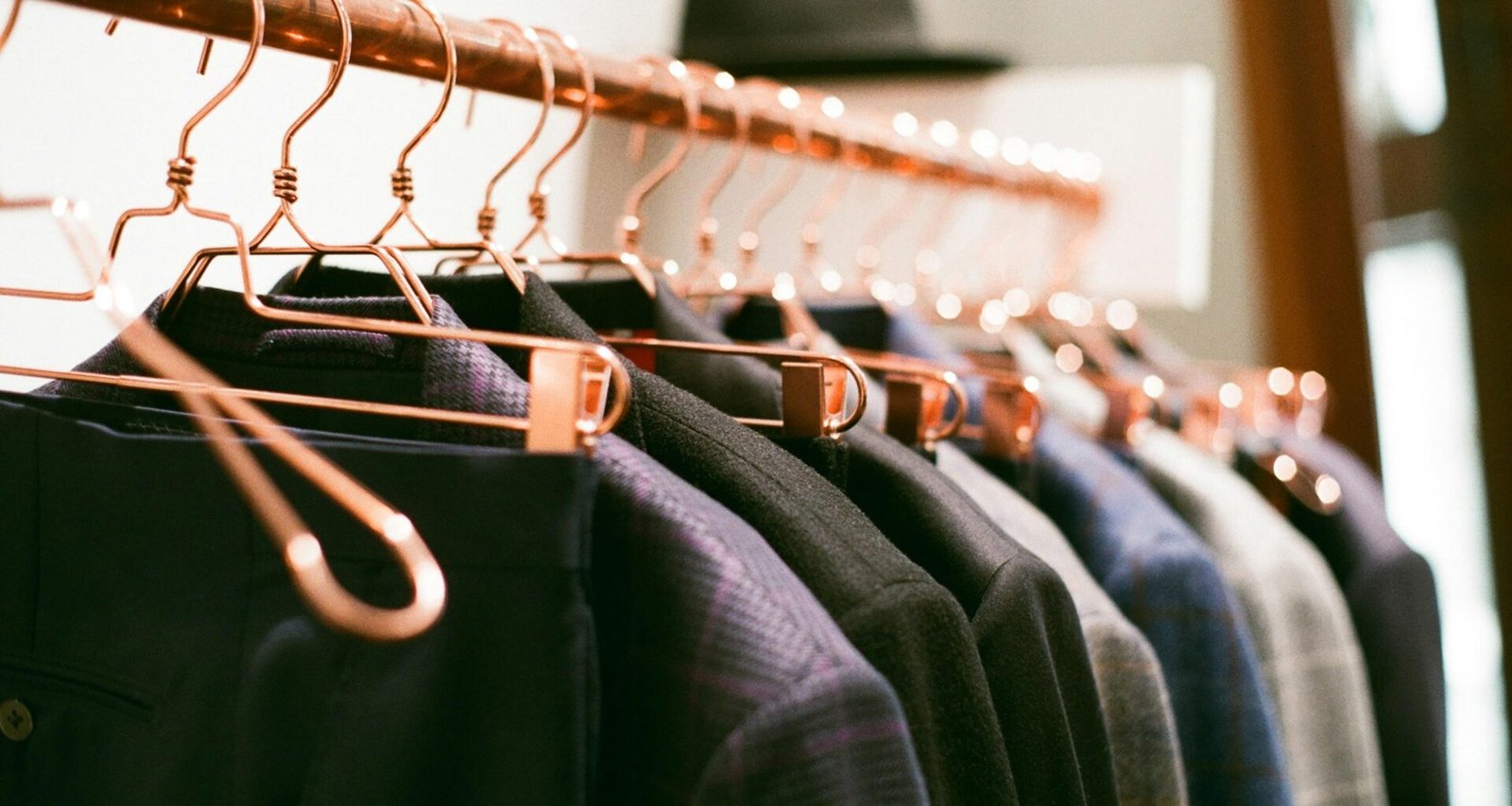 Ein Kleiderständer mit verschiedenen Kleidern und einem Hut auf hellem Hintergrund, abgebildet für einen Artikel über Interior Trends.