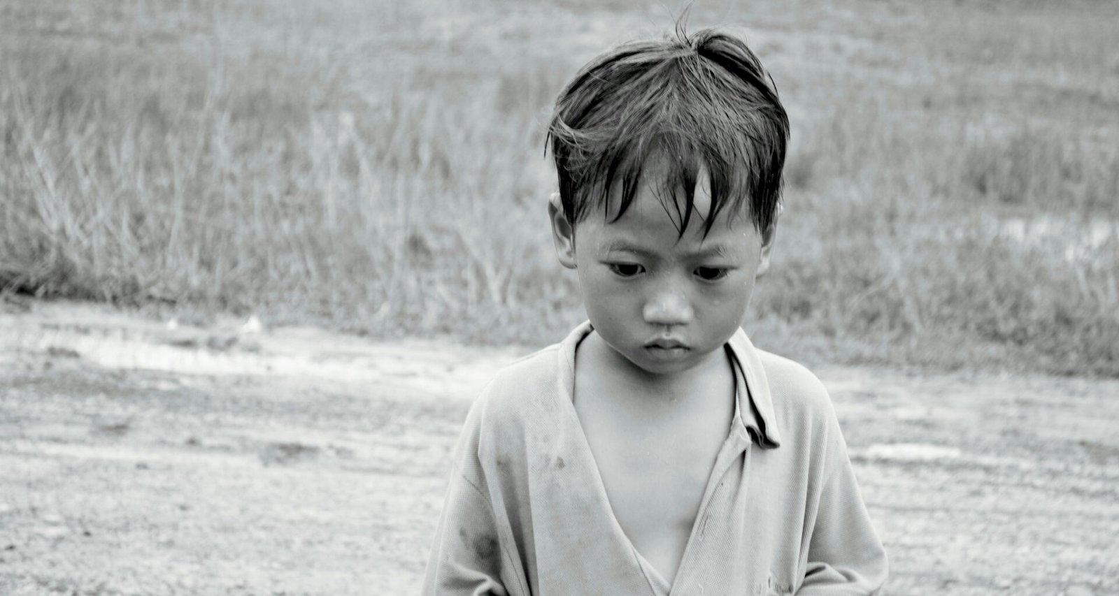 Ein Junge steht auf einem weiten Feld und hält ein Frisbee in der Hand, bereit zum Werfen an einem sonnigen Tag.