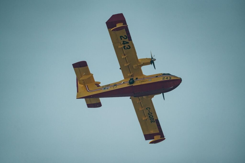 Kleines gelbes Flugzeug fliegt durch einen wolkenlosen, blauen Himmel, aufgenommen aus der Bodenperspektive