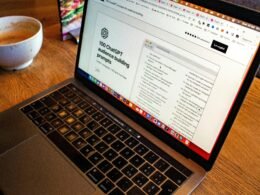 Ein geöffneter Laptop steht auf einem hellen Holztisch, bereit für die Arbeit oder Online-Kommunikation im Homeoffice.