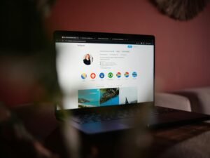 Ein Laptop steht auf einem hölzernen Tisch, fotografiert aus der Seitenperspektive in einem hellen Raum.