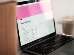 Ein Laptop steht auf einem Holztisch, daneben eine Tasse Kaffee – Symbol für Arbeit und Technologie im Büroalltag.