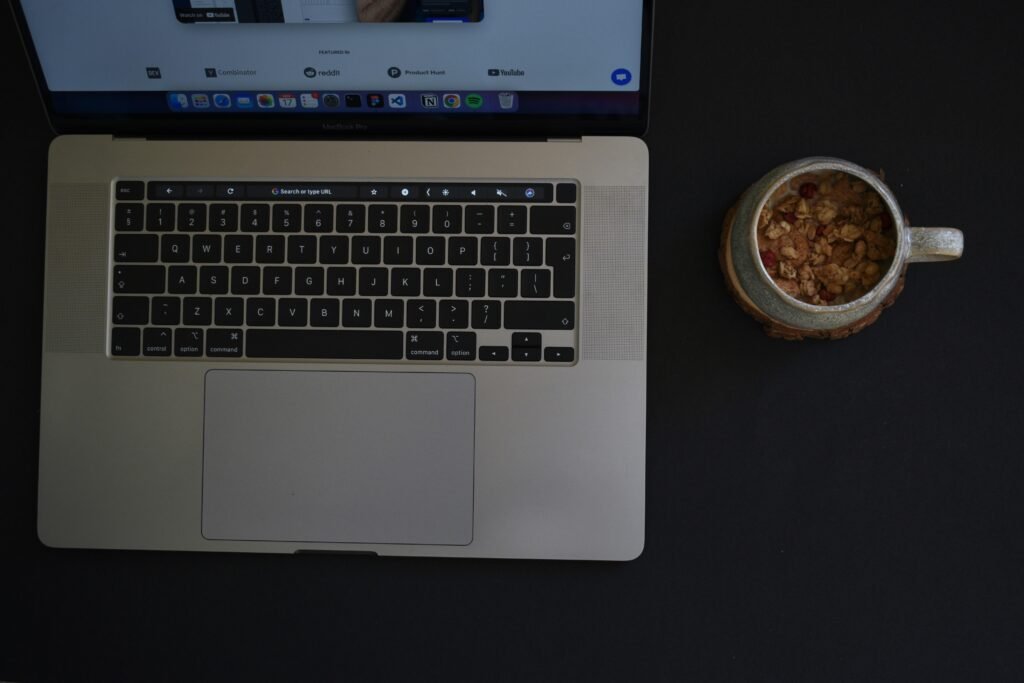 Ein Laptop steht auf einem Tisch, daneben eine Schale mit Essen – modernes Arbeiten und Pausen im Alltag am Arbeitsplatz.