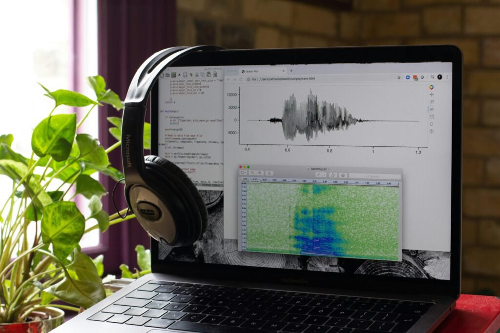 Ein silberner Laptop mit schwarzen Kopfhörern liegt auf einem Schreibtisch, perfekte Technik für multimediales Arbeiten