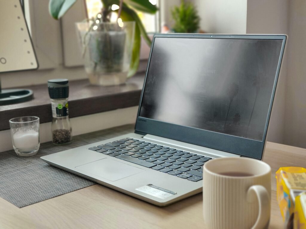 Ein moderner Laptop steht auf einem hölzernen Schreibtisch in einem gut beleuchteten Raum, bereit für berufliche oder private Nutzung.