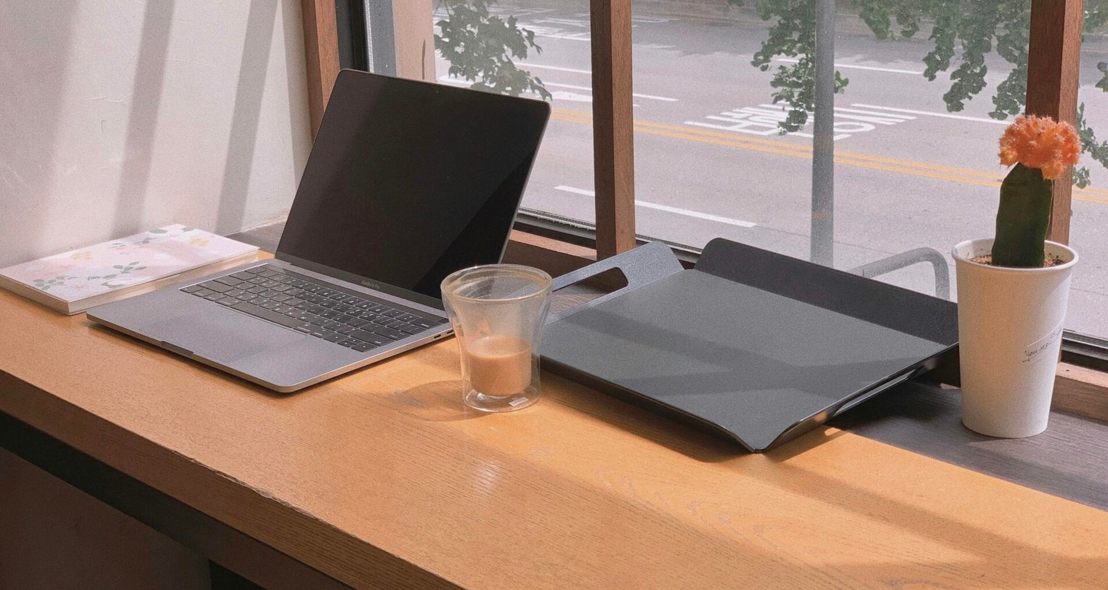Ein Laptop und ein Glas Wasser stehen nebeneinander auf einem schlichten Tisch in einer zeitgemäßen Büroumgebung.