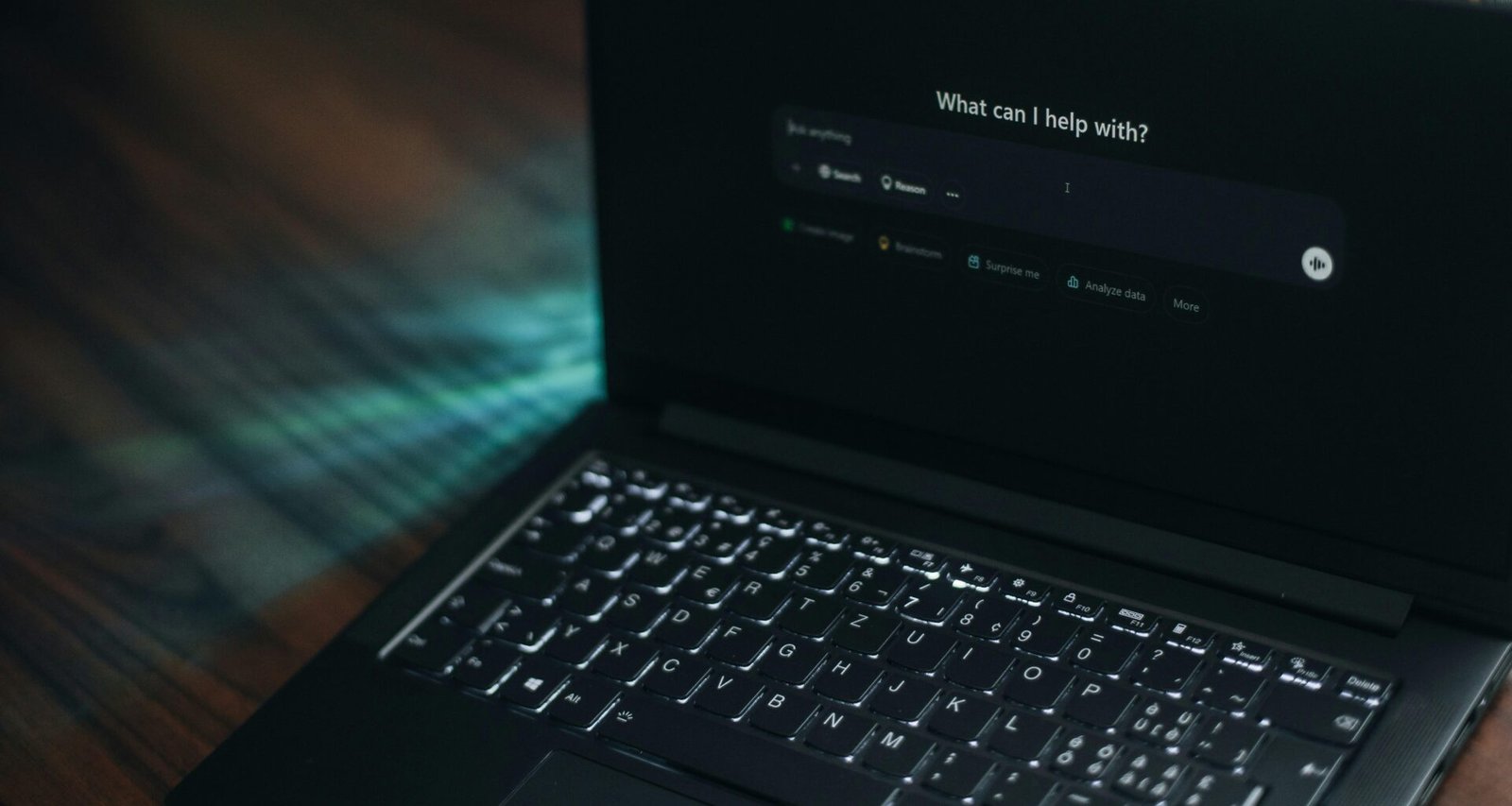 Ein geöffneter Laptop mit einer angezeigten Suchleiste und der Frage, wie geholfen werden kann, auf einem Schreibtisch