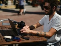 Ein Mann sitzt am Schreibtisch und nutzt einen Laptop für digitale Aufgaben und Kommunikation.