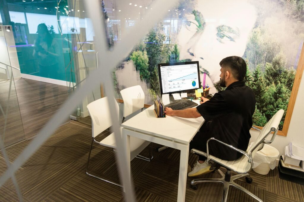 Ein Mann sitzt an einem Schreibtisch und arbeitet am Computer in einem modernen Büro, aufgenommen von Cova Software.