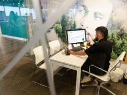 Ein Mann sitzt an einem Schreibtisch und arbeitet am Computer in einem modernen Büro, aufgenommen von Cova Software.