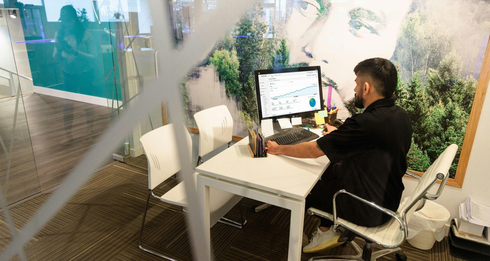 Ein Mann sitzt an einem Schreibtisch und arbeitet am Computer, typische Szene aus dem modernen Arbeitsalltag im Büro.