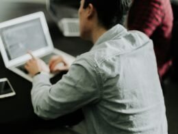 Ein Mann sitzt an einem Tisch und verwendet einen Laptop, um digitale Aufgaben oder Arbeiten zu erledigen.