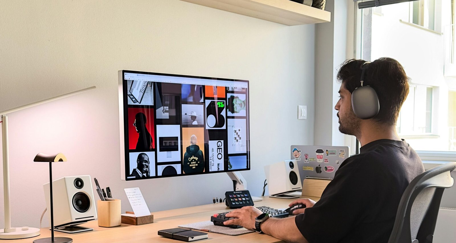 Ein Mann mit Kopfhörern sitzt an einem Schreibtisch und arbeitet an einem Laptop in einem modernen Büro