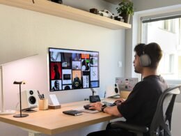 Mann mit Kopfhörern sitzt an einem Schreibtisch und arbeitet am Computer in einem modernen Büro oder Homeoffice.