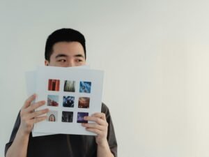 Ein Mann sitzt und hält ein Buch vor sein Gesicht, sodass nur seine Hände und das Buch sichtbar sind