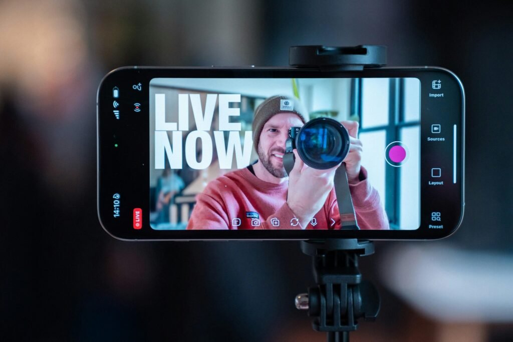 Ein Mann nimmt sich mit einem Smartphone auf, das auf einem Stativ befestigt ist, ideal für Videoproduktion oder Vlogging.