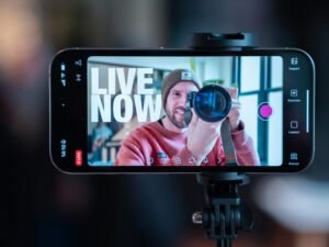 Ein Mann filmt sich mit einem Smartphone auf einem Stativ und erstellt so eigene Videoaufnahmen für Social Media.