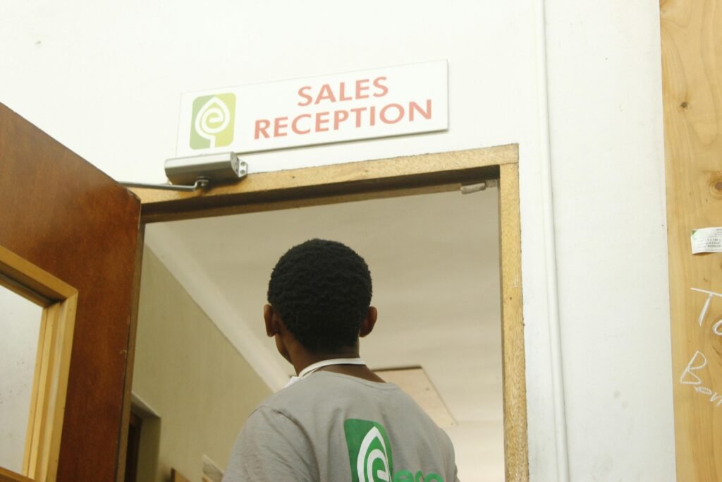 Ein Mann geht auf die Tür einer Verkaufsrezeption zu, moderner Innenraum und klar strukturierter Eingangsbereich