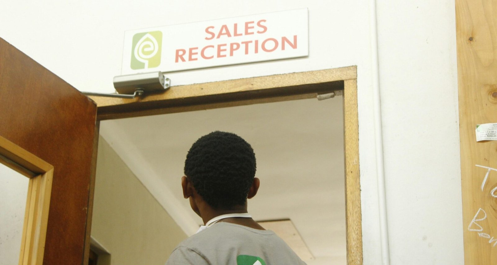 Ein Mann geht auf die Tür einer Verkaufsrezeption zu, moderner Innenraum und klar strukturierter Eingangsbereich