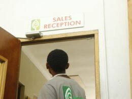 Ein Mann geht auf die Tür einer Verkaufsrezeption zu, moderner Innenraum und klar strukturierter Eingangsbereich