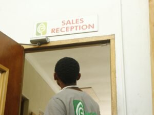 Ein Mann geht auf die Tür einer Verkaufsrezeption zu, moderner Innenraum und klar strukturierter Eingangsbereich