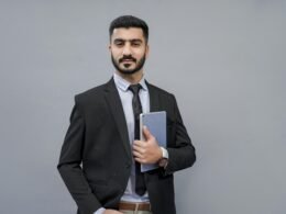 Ein Mann steht und hält ein Buch in den Händen, Fokus auf das Buch und seine Geste, ideal für Beiträge über digitales Lernen.