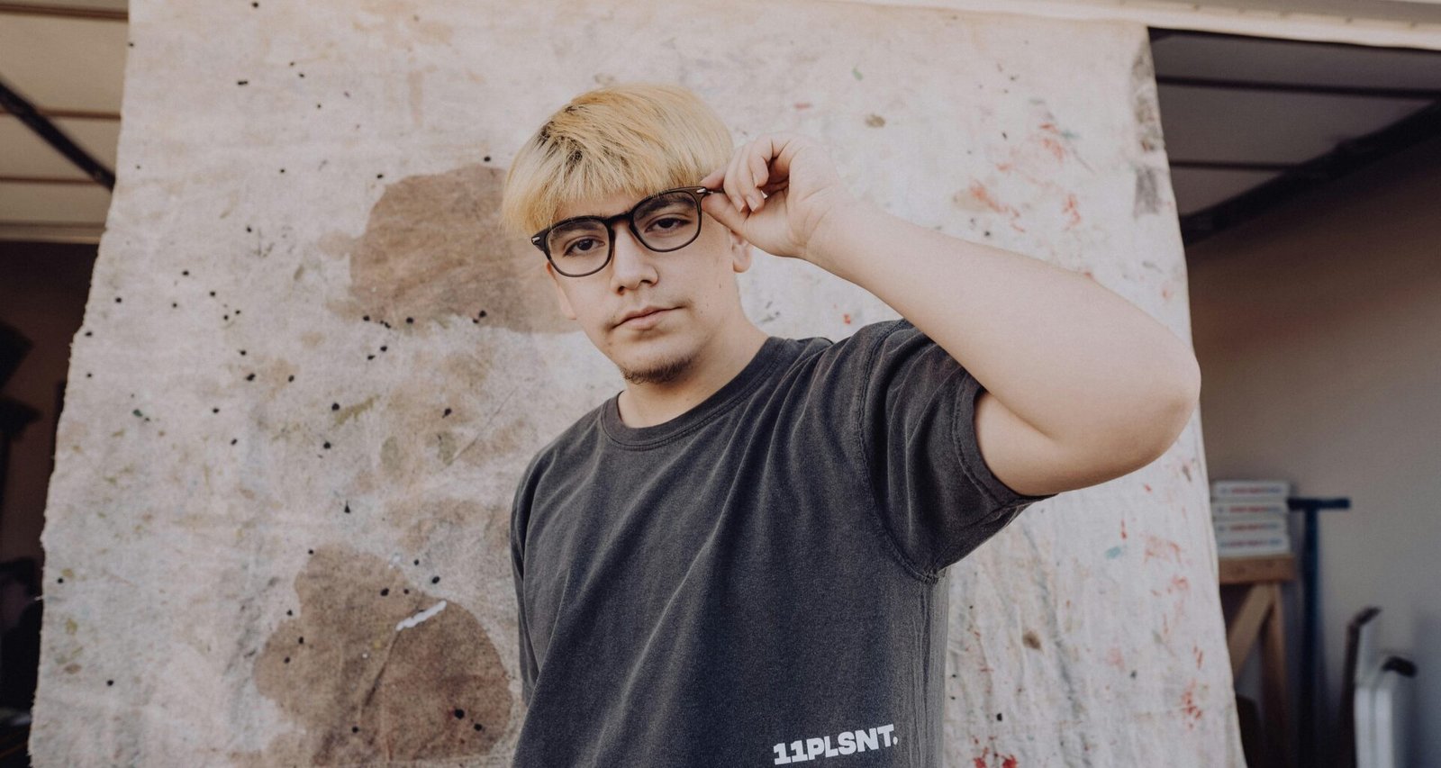 Mann mit Brille steht vor einer neutralen Wand, geeignet als Symbolbild für Themen rund um Technologie und Online Marketing