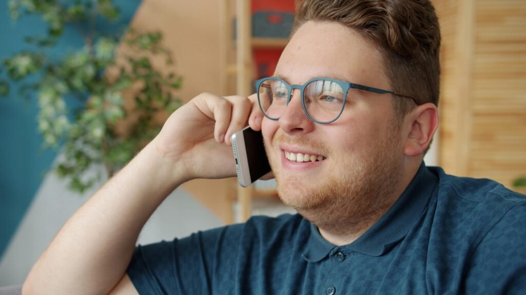 Mann mit Brille spricht im Innenraum am Smartphone – Fokus auf moderne Business-Kommunikation im Alltag