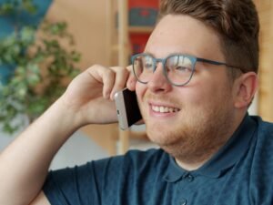 Mann mit Brille spricht im Innenraum am Smartphone – Fokus auf moderne Business-Kommunikation im Alltag