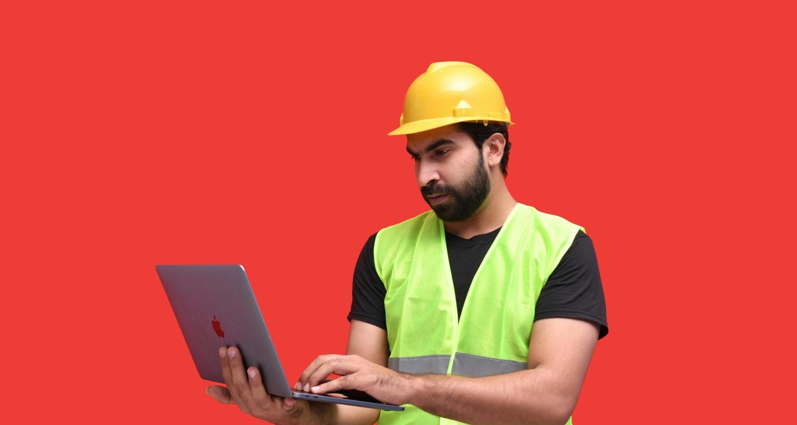 Ein Mann mit gelbem Bauhelm hält ein Tablet und steht auf einer Baustelle, moderner Technikeinsatz im Bauwesen