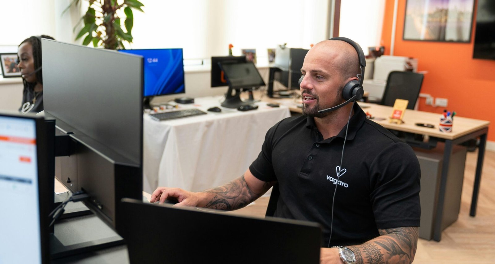 Ein Mann mit Headset arbeitet konzentriert an seinem Computer in einem modernen Büro oder Homeoffice.