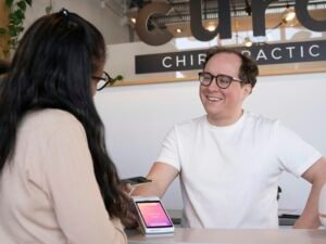 Ein Mann sitzt an einem Schreibtisch und spricht mit einer Frau in einem modernen Büro. Thematisch geeignet für Arbeitswelt- oder Kommunikationsthemen.